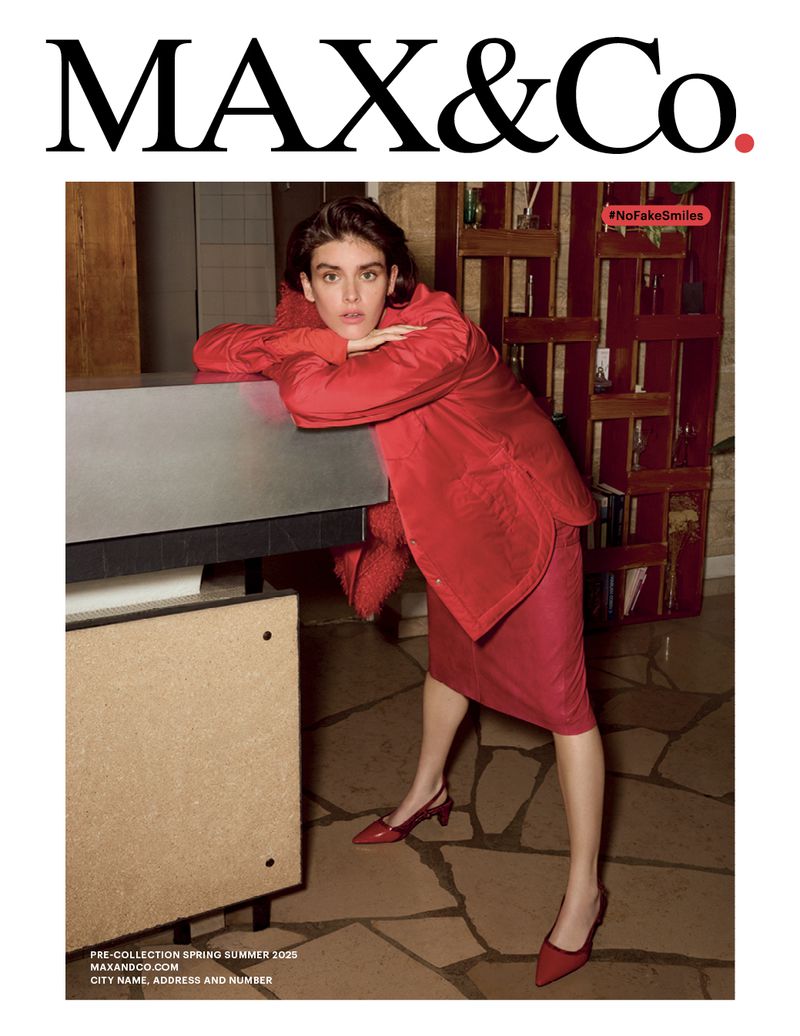 A brunette model poses indoors wearing a red jacket and skirt, alongside a beige cabinet. Max&Co brand logo at the top.