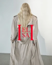 Model Elsa Hosk facing away, wearing a long beige trench coat against a white studio background with bold red typographic logo.