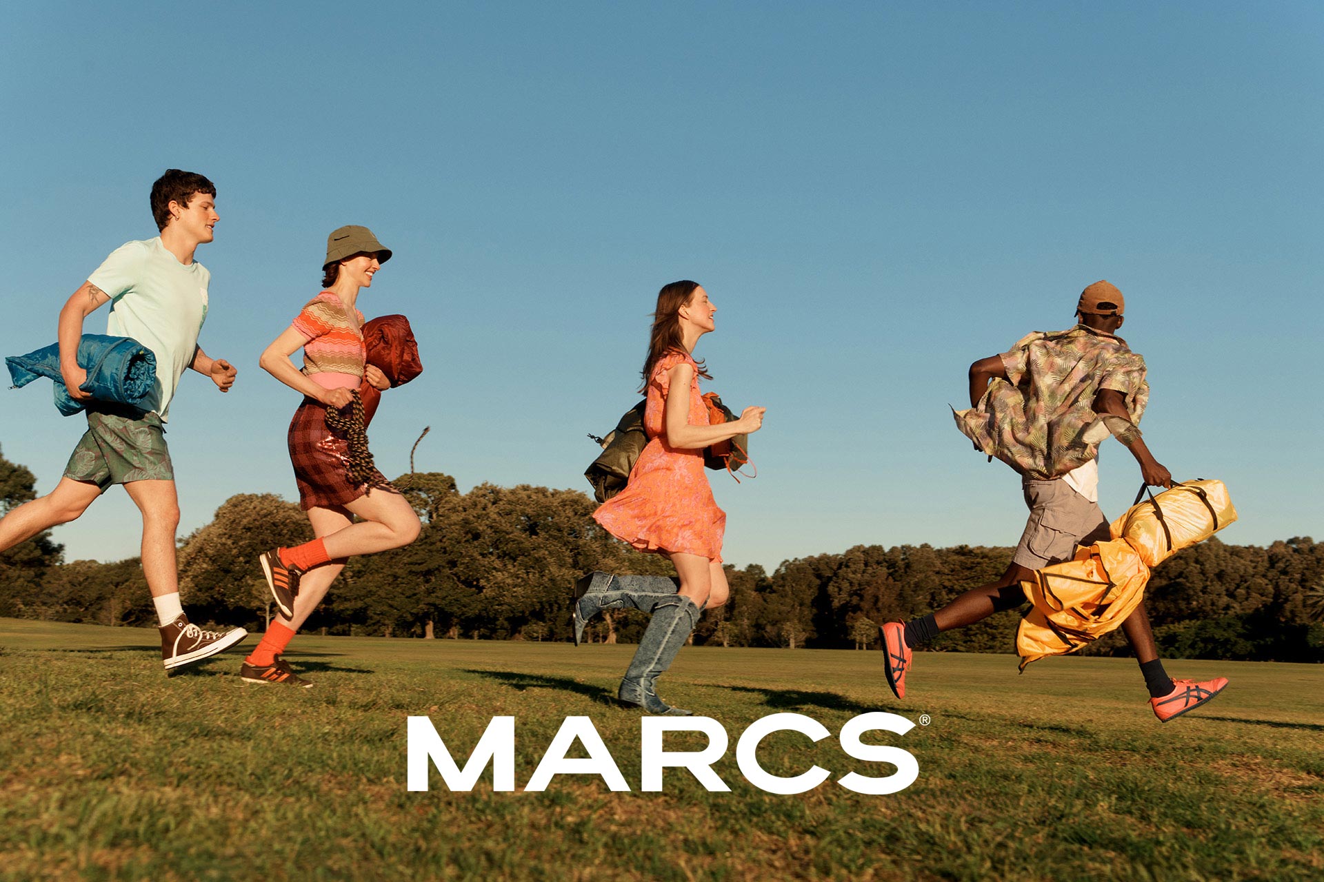 Four people running across a grassy field, carrying camping gear, beneath a clear blue sky, advertising MARCS brand.