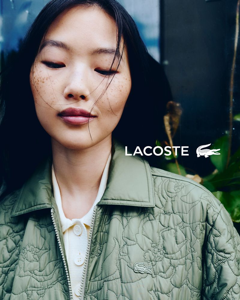 Close-up of an Asian female model showcasing Lacoste outerwear with floral quilted pattern and the brand's iconic crocodile logo.