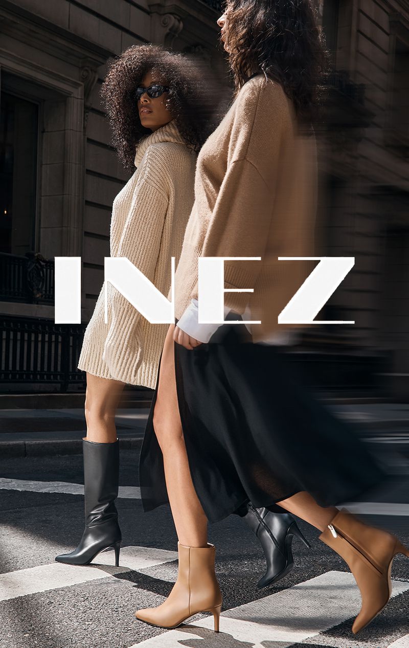 Two women in stylish autumn outfits are walking on a pedestrian crossing. One is wearing boots and a sweater dress.