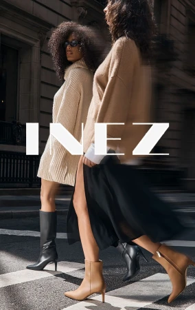 Two women in stylish autumn outfits are walking on a pedestrian crossing. One is wearing boots and a sweater dress.