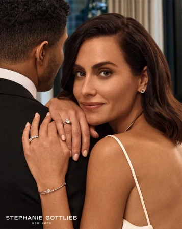 Woman wearing a diamond ring and bracelet poses with a man in a black tuxedo in jewelry advertisement for Stephanie Gottlieb.