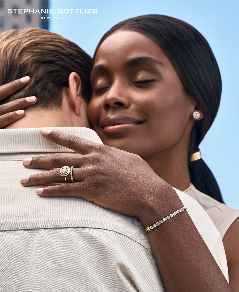 Jewelry ad featuring an African American woman embracing a Caucasian man with diamond ring, tennis bracelet, and stud earrings.