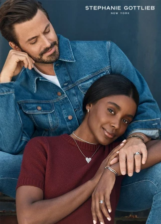 A man in a denim jacket embracing a woman wearing a maroon sweater and diamond jewelry for Stephanie Gottlieb