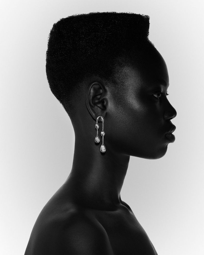 Striking profile portrait of an African American woman showcasing elegant silver drop earrings against a stark white backdrop.