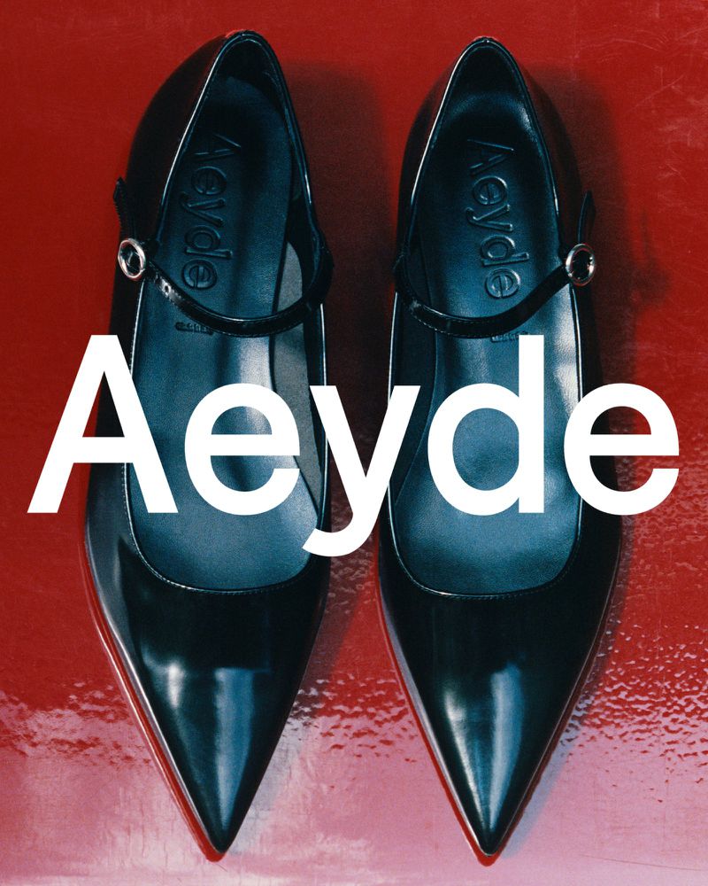 A pair of black Aeyde patent leather pointed-toe pumps with a strap are displayed on a glossy red background with large white text overlay.
