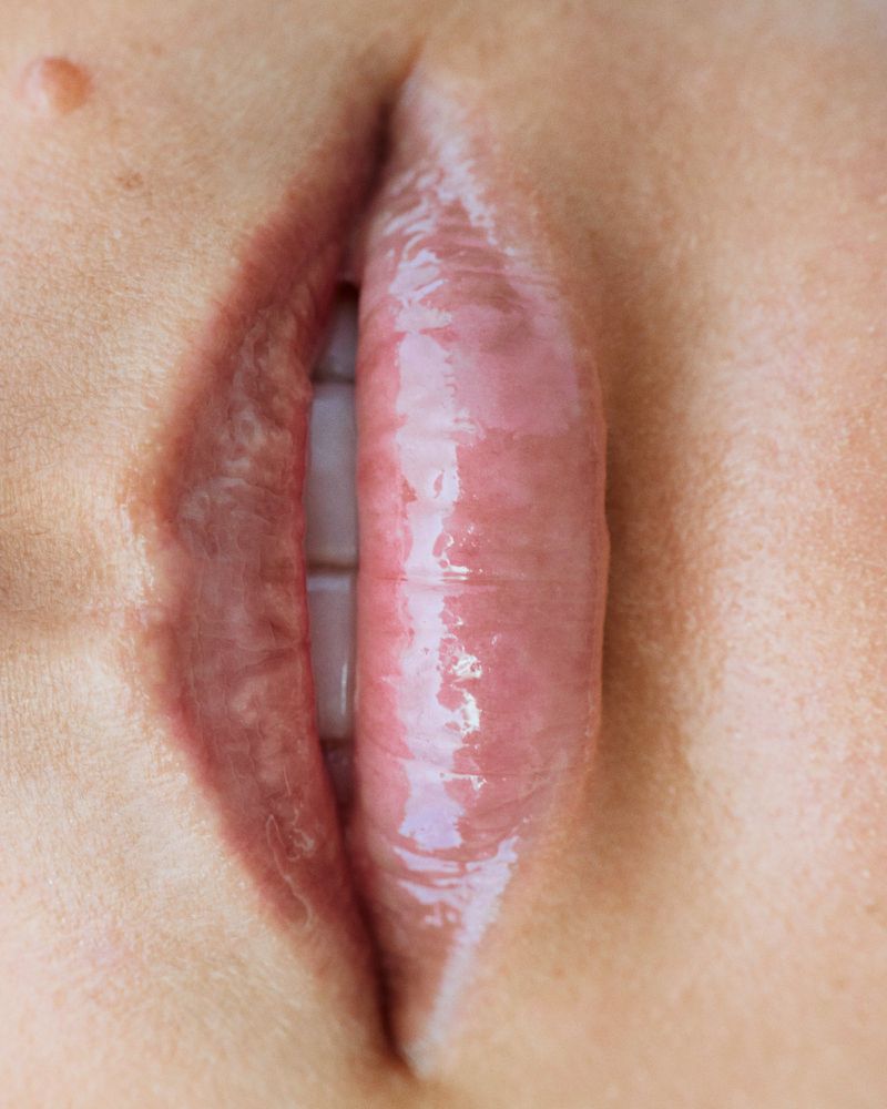 Extreme macro close-up of glossy pink lips and teeth for the H&M Wellness Spring 2025 campaign.