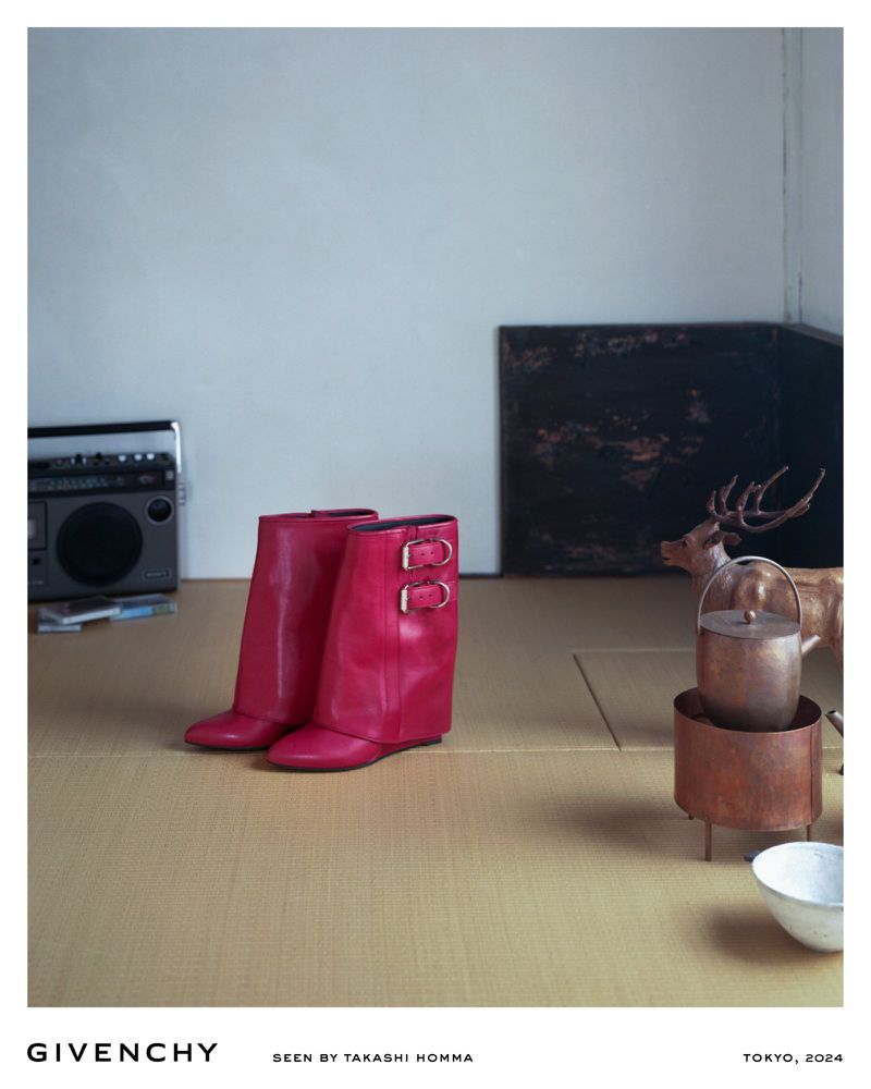Fashion editorial shot of a pair of pink Givenchy boots on a woven mat, set against a minimalist backdrop with vintage audio and decor.