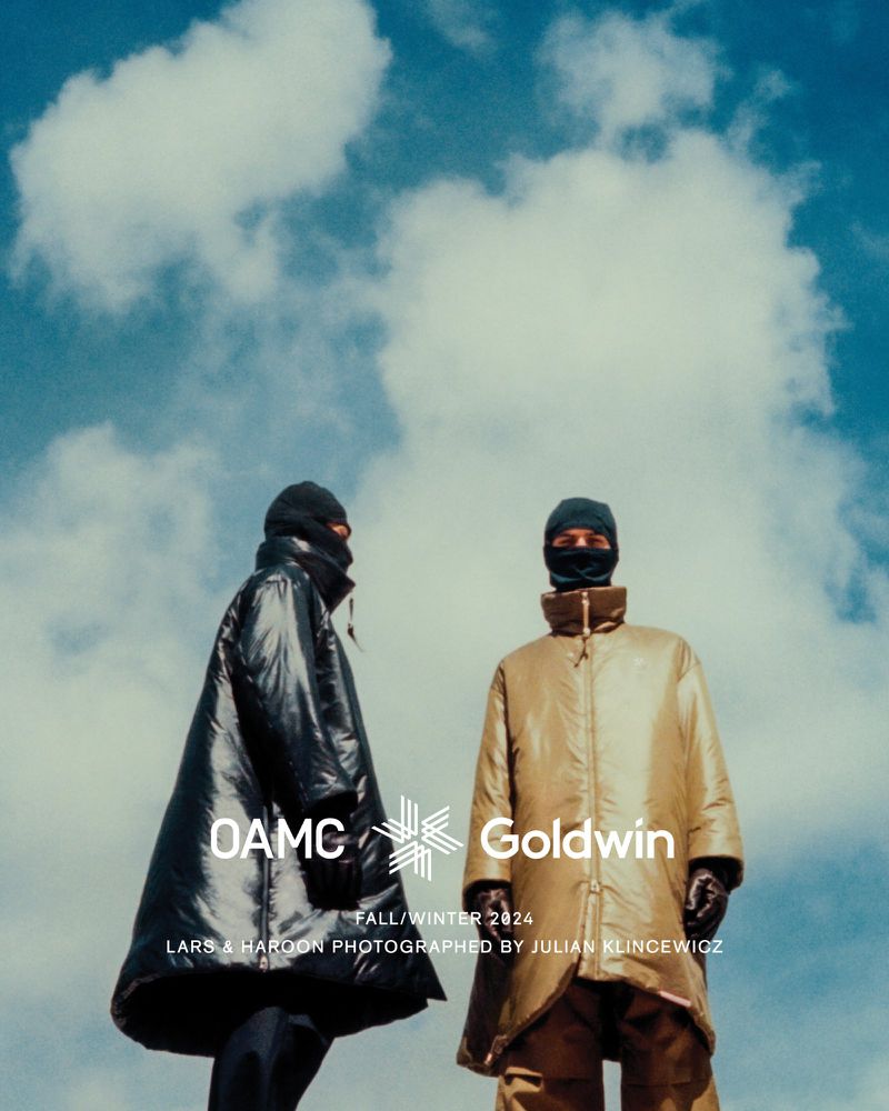 Two figures in black balaclavas and outerwear stand against a cloudy sky, showcasing OAMC and Goldwin's Fall/Winter 2024 collection.
