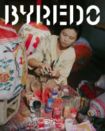 Woman in beige top painting traditional red and white paper lanterns surrounded by art supplies for the Byredo CNY campaign.