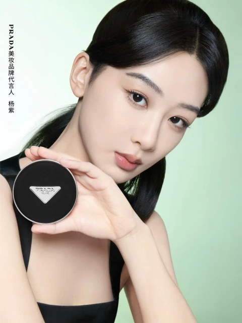 Close-up of a young Asian woman holding a Prada compact makeup case against a soft green backdrop in a beauty advertising campaign.