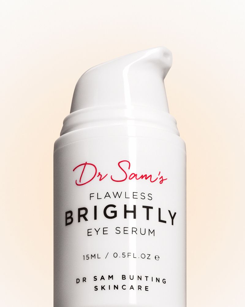 Close-up of a white bottle of Dr. Sam's Flawless Brightly Eye Serum with red and black text on a light peach background.