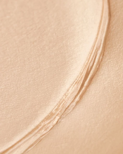 Close-up of light beige fabric with smooth texture and folds, creating soft curves and subtle shadows in a minimalist composition.