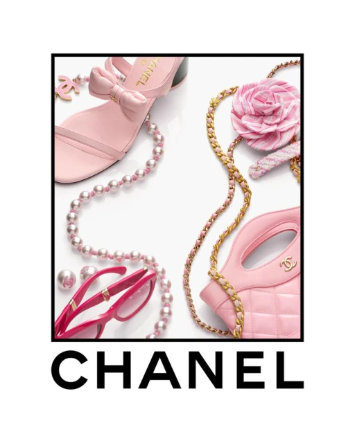 Still life of pink Chanel sandal, handbag, sunglasses, necklace, and flower with gold chain on a white background, studio lighting.