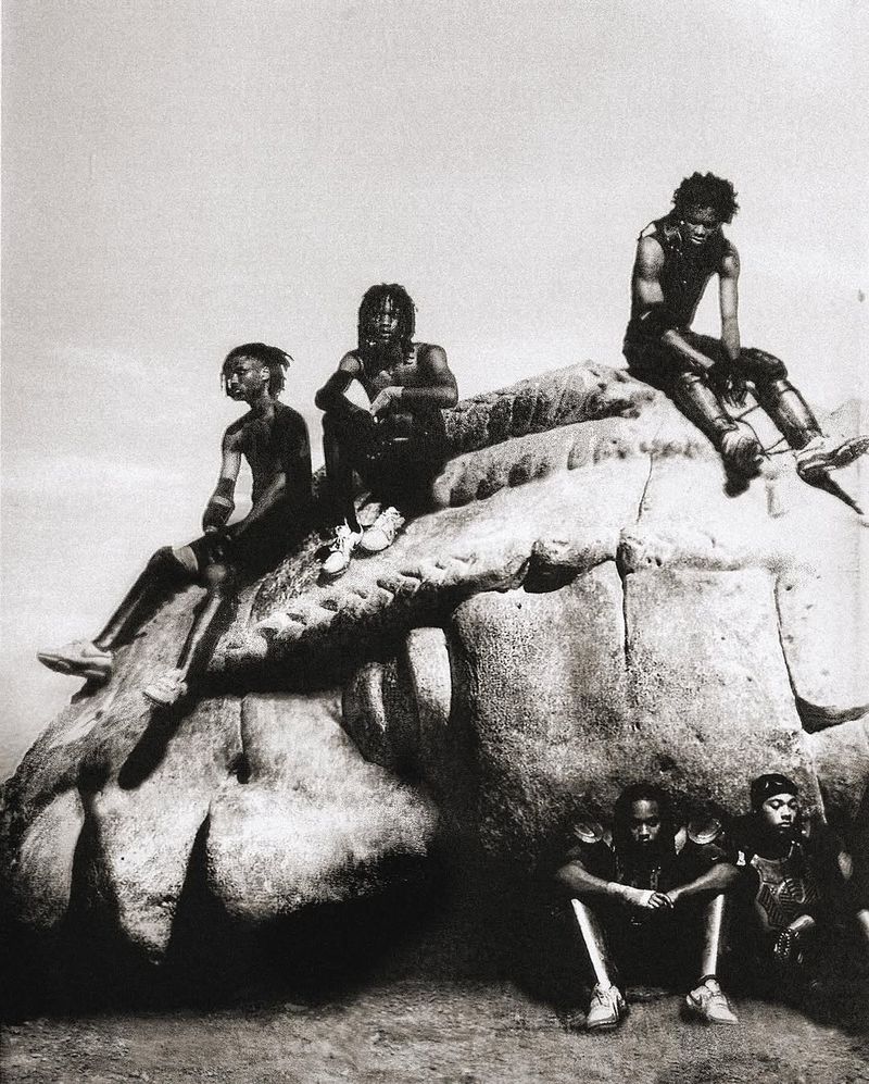 Monochromatic group portrait of six African American people sitting on a rock formation under an overcast sky, evoking a sense of solidarity.