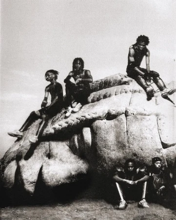 Monochromatic group portrait of six African American people sitting on a rock formation under an overcast sky, evoking a sense of solidarity.
