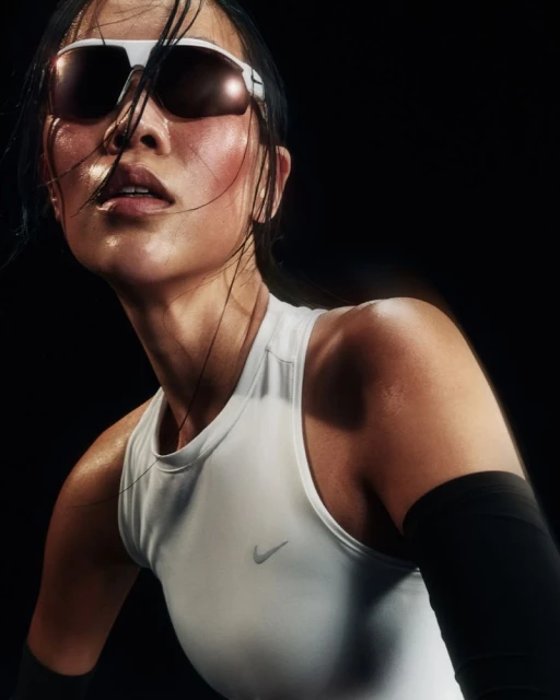 Sweaty athlete posing in a white tank top and sunglasses against a black background in a studio portrait, showcasing fitness and determination.