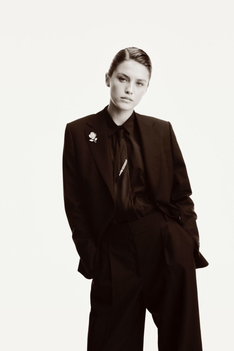 Model wearing dark suit jacket and tie against a plain white background for Boucheron jewelry project.