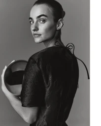 Model Maartje Verhoef holding a round object wearing a dark garment against a grey background for Marc O'Polo