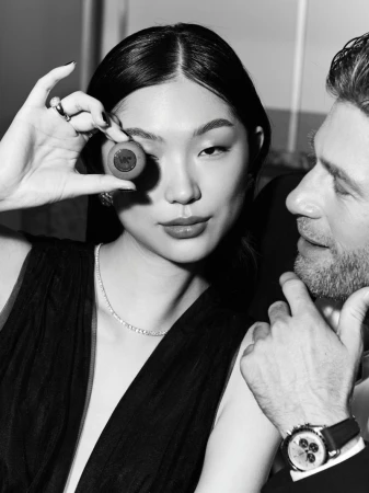 Elegant portrait in black and white of an Asian woman with brown eye contact lens and a man with a watch, wearing formal attire.