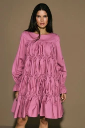 Model Raica Oliveira wearing a pink smocked dress against a solid neutral background for the Armargentum Campaign photographed by Olga Rubio Dalmau.