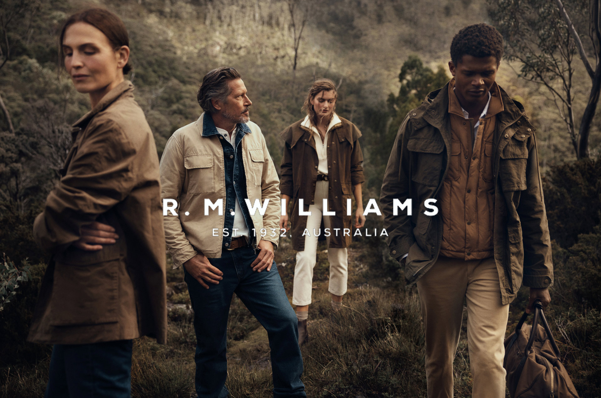 Four people in outdoor apparel stand in a field with trees in the background, showcasing the R.M. Williams brand and its Australian roots.