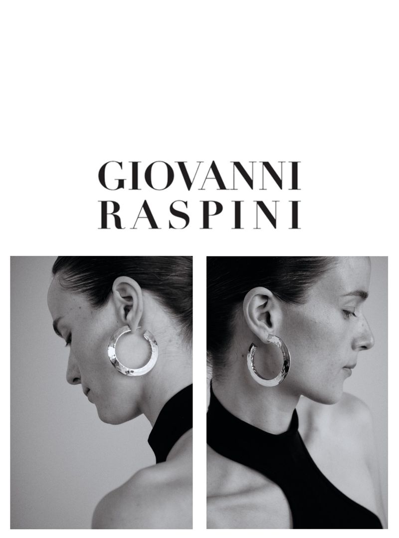 Black and white studio shot of a woman with elegant silver hoop earrings, sleek hairstyle, and black turtleneck top.