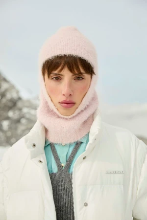 Model wearing a fuzzy pink balaclava and white puffer jacket with an outdoor mountain backdrop