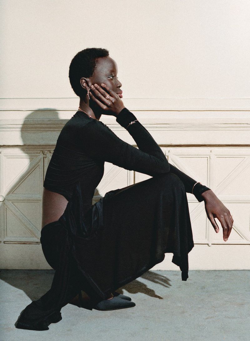 Model in a black outfit crouching against a neutral wall with architectural panels for Tiffany & Co.