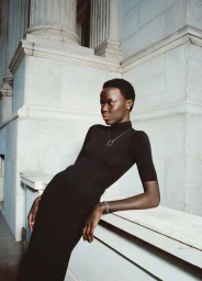 Model in a black turtleneck leaning against classical stone architecture wearing silver jewelry