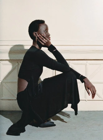 Model in a black outfit crouching against a neutral wall with architectural panels for Tiffany & Co.