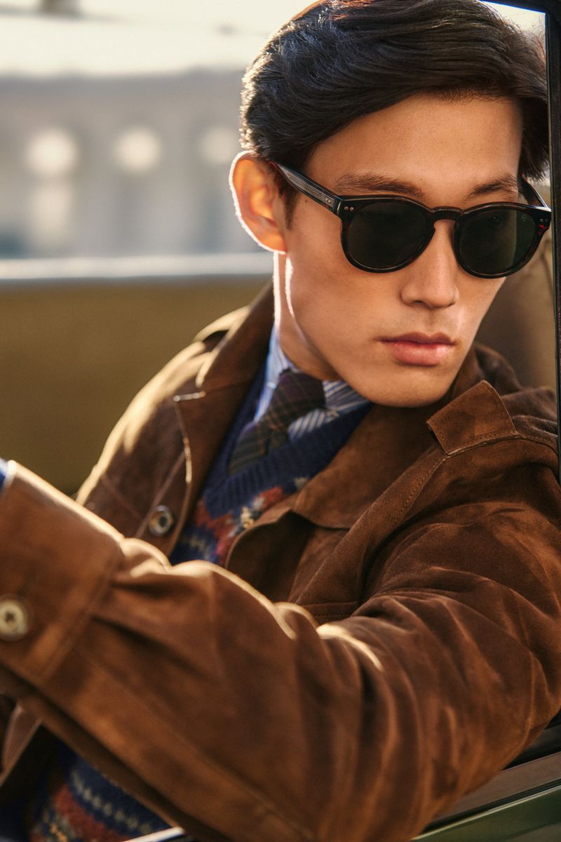 Man wearing sunglasses and a brown suede jacket seated inside a vehicle for Ralph Lauren Purple Label F/W 24