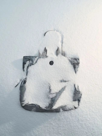 Fashionable grey tote bag dusted with snow on white backdrop, creating a minimalistic winter fashion statement in a cool aesthetic.