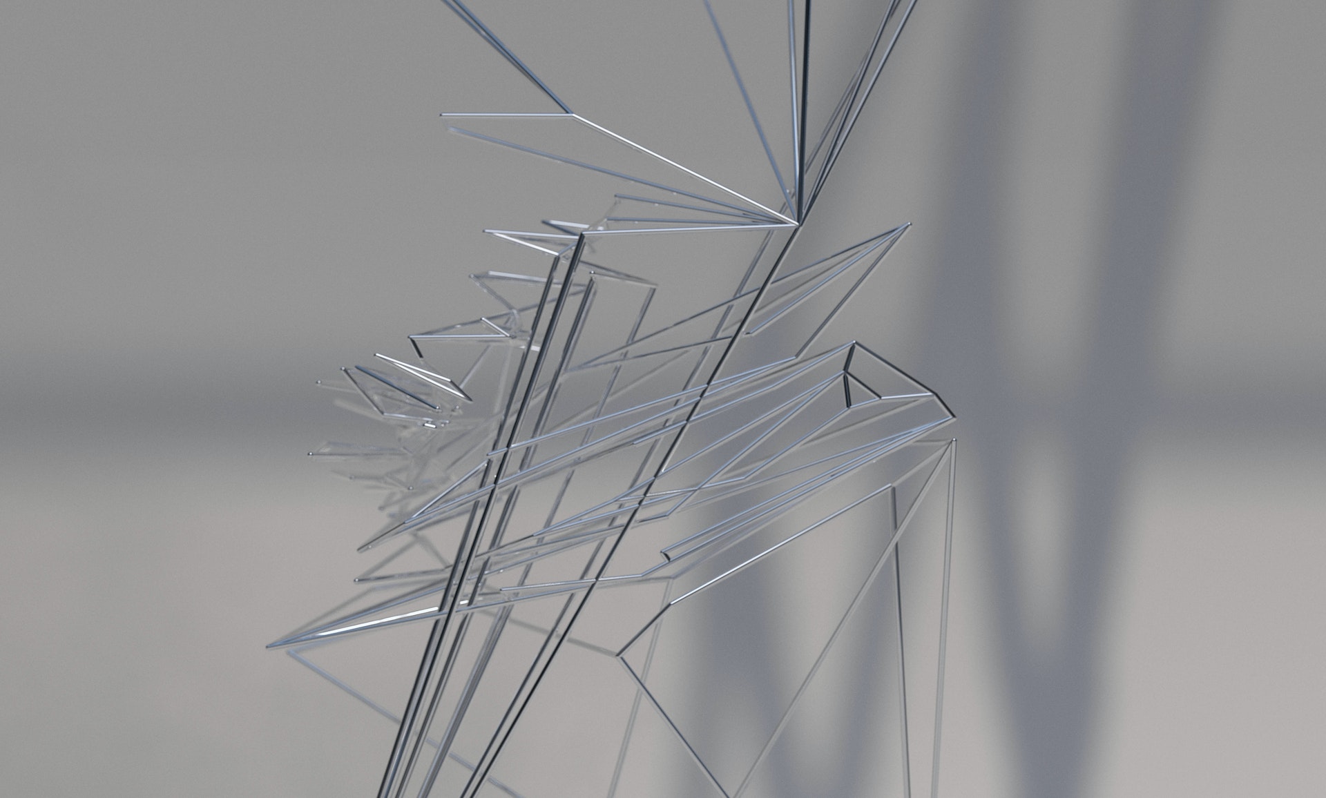 Abstract silver metallic structure with geometric shapes and lines against a gray background, creating a modern and minimalist design.