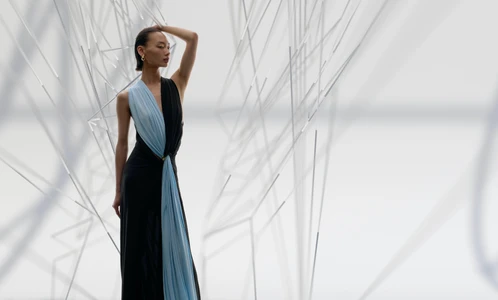 Model in a black and light blue split gown posing amidst geometric white structural elements