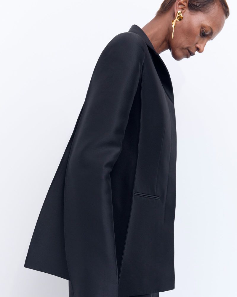 Model wearing a black blazer and gold earring against a white background for Net-A-Porter Khaite PS25