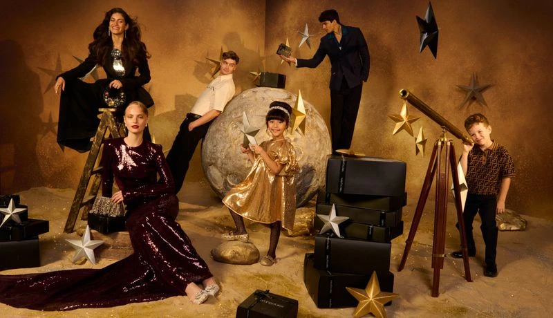 Group of models posing in a photo studio with props. Two adult women, two adult men, a girl, and a boy are present in the shot.