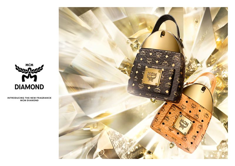 Two MCM Diamond perfume bottles, one brown and one peach, are displayed against a blurred diamond-faceted background in a product shot.