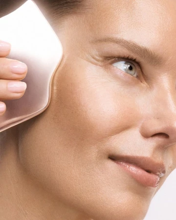 Close-up of a woman receiving a facial massage with a rose quartz gua sha tool, highlighting skincare and beauty routine.