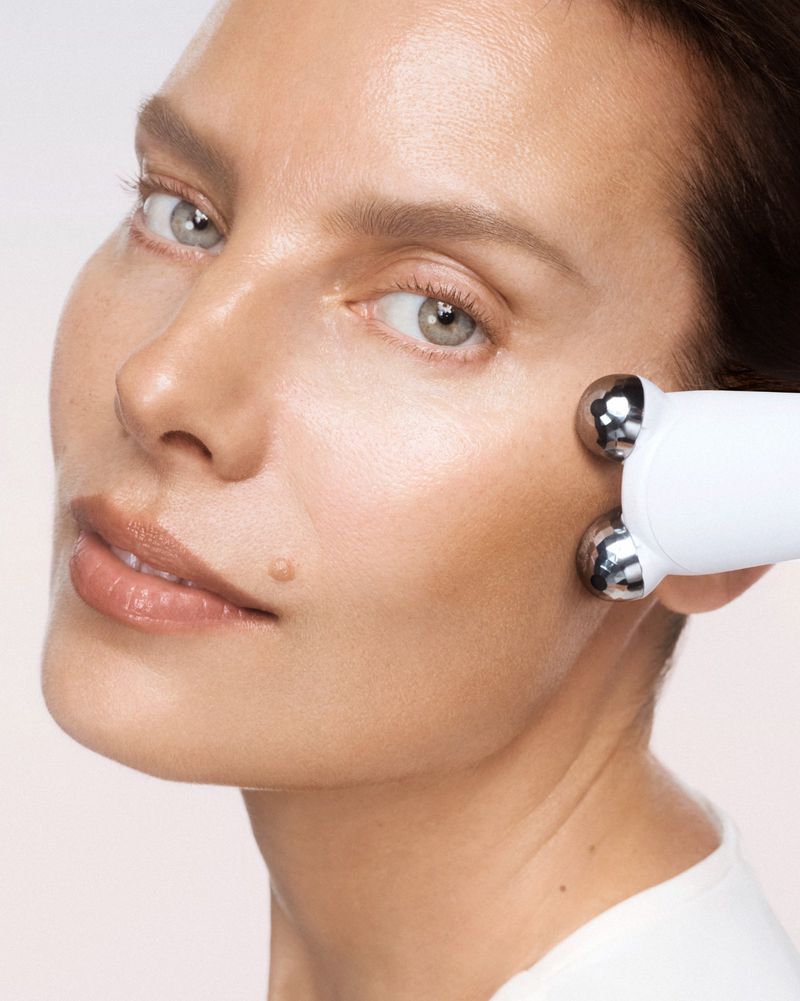 Close-up of a woman receiving a facial massage with a white massaging tool, focusing on skincare and beauty treatment.