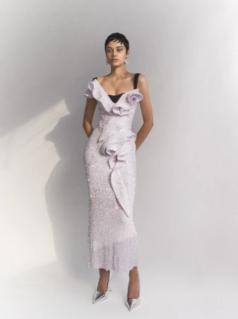 Elegant adult female in a shimmering lilac gown with silver heels, posing in a brightly lit studio setting with a neutral backdrop.
