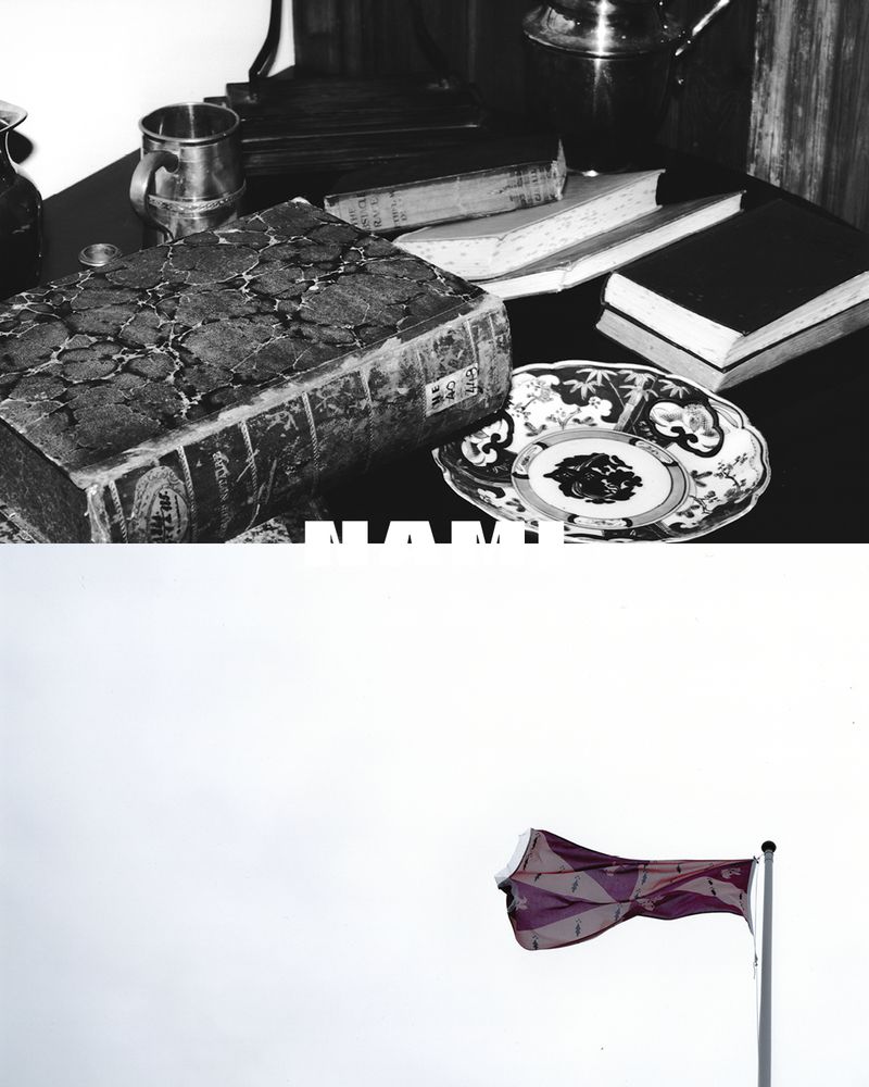 Still life photograph features an old book, metal mug, decorative plate, and UK flag against a cloudy sky, rendered in grayscale.