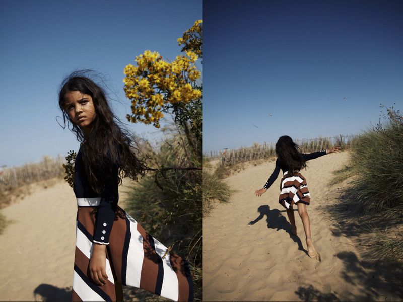 A young girl wearing a striped skirt and dark top is seen in two images, one a medium shot, the other from behind in full stride on a beach.
