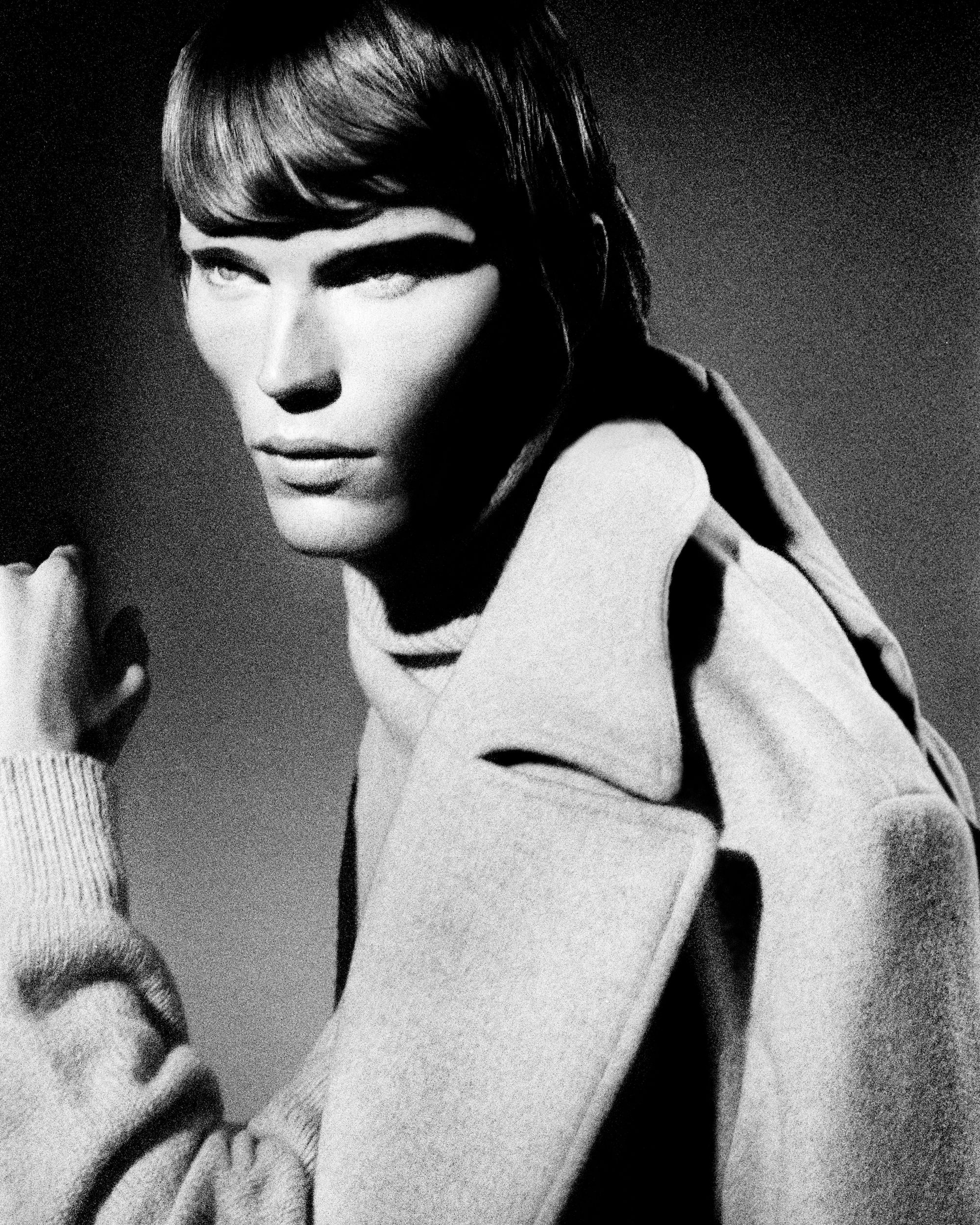 Monochrome portrait of male model Jordan Barrett wearing a heavy coat and turtleneck under dramatic directional lighting.