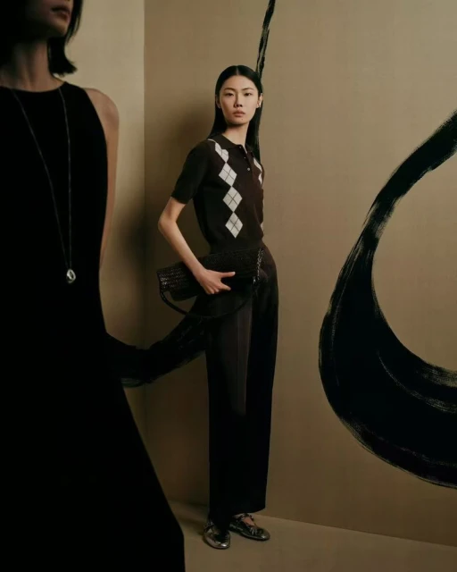 Two Asian women in a studio setting, showcasing fashion attire with one woman in a black dress and another in a patterned sweater.