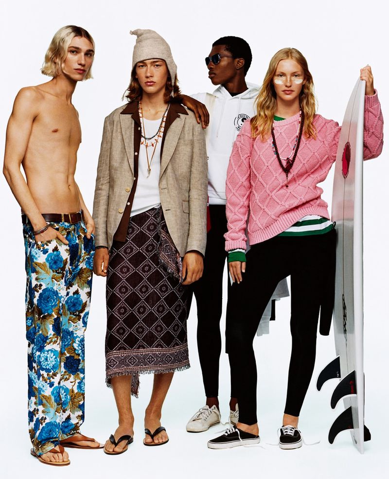 Four people in fashionable beachwear pose in a photo studio. One holds a surfboard, and they wear summer colors and diverse styles.