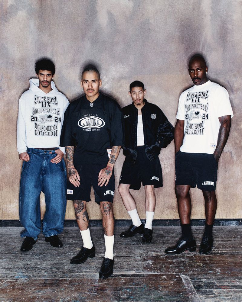 Four diverse men in athletic streetwear stand indoors against a textured wall, showcasing football-themed fashion apparel for the Super Bowl.