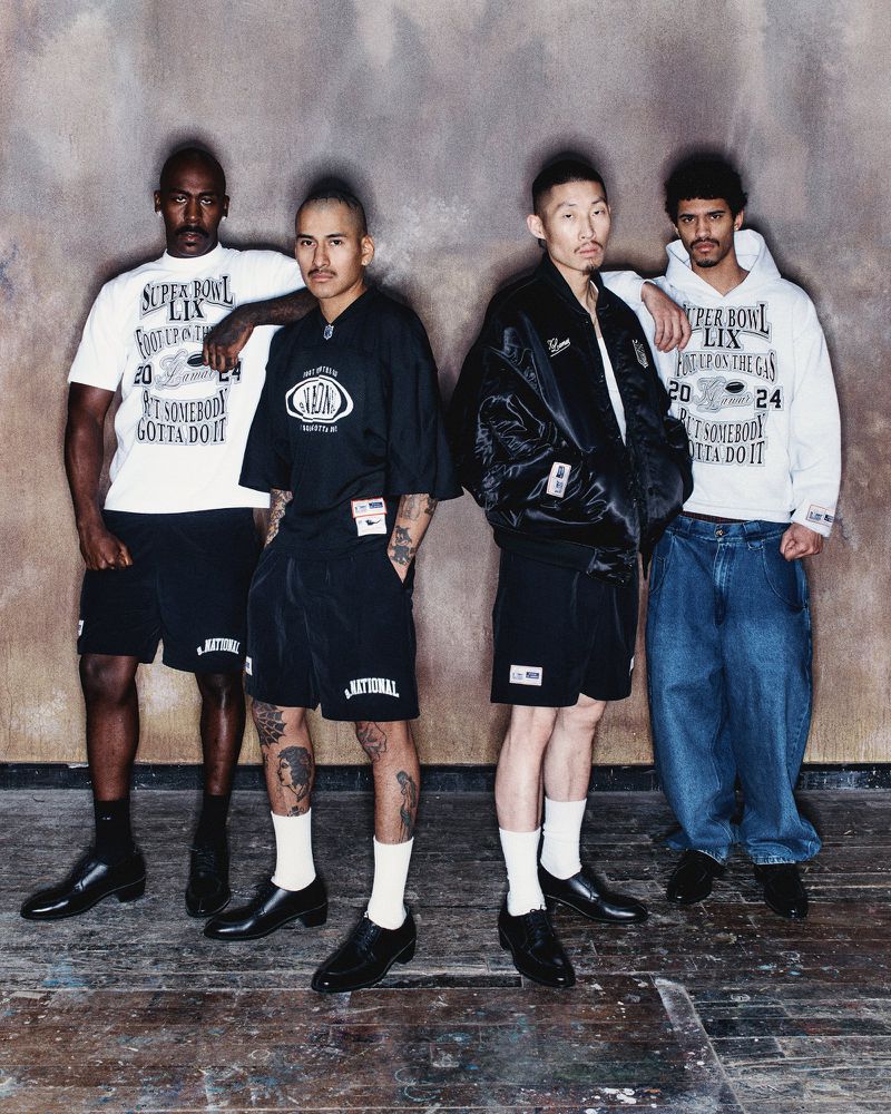 Four male models posing in streetwear against a mottled brown studio backdrop for Willy Chavarria.