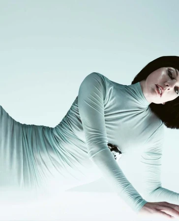 Milla Jovovich in a fitted pale blue turtleneck dress posing against a light background for Vogue Czechoslovakia.